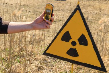 Eastern Europe, Ukraine, Pripyat, Chernobyl. Checking radiation monitors (dosimeters) near a sign warning of radiation danger. April 10, 2018. clipart