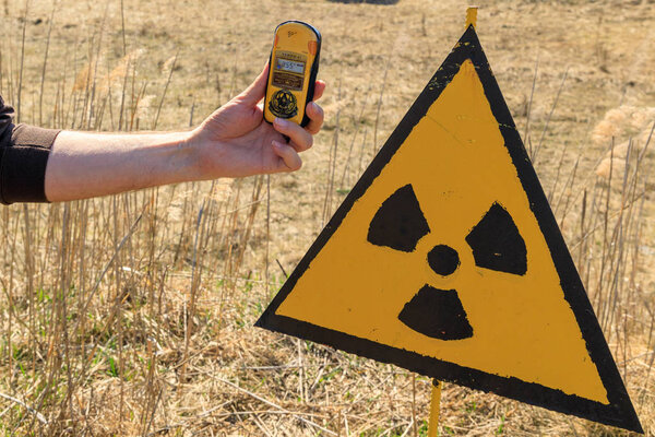 Eastern Europe, Ukraine, Pripyat, Chernobyl. Checking radiation monitors (dosimeters) near a sign warning of radiation danger. April 10, 2018.