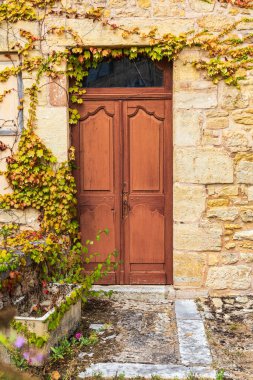 Avrupa, Fransa, Dordogne, Hautefort. Hautefort kasabasındaki taştan bir evde kahverengi bir kapı..