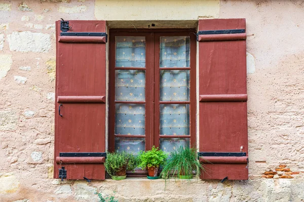 Europe, France, Dordogne, Hautefort. A brown shuttered window on a house in the town of Hautefort.