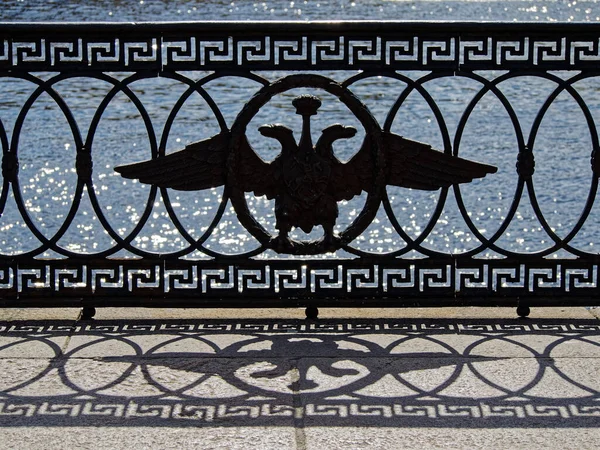 Cast-iron fence of the Neva embankment with the symbol of the Russian Empire-a two-headed eagle under a crown. The heart of old Saint Petersburg.