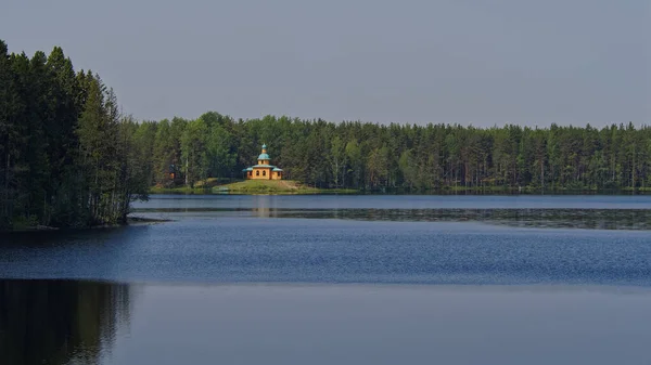 Göl kıyısındaki tahta tapınağın manzarası. Leningrad bölgesindeki Alexander-Svirsky manastırı.