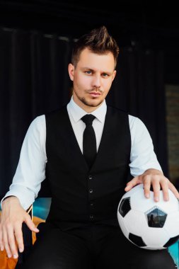 Bir takım elbise ve bir futbol topu şık spor adamı. Bir çatı duvar arka planı.