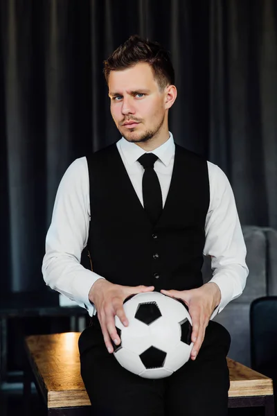 ビジネス スーツとサッカー ボールでスタイリッシュなアスレチック男。ロフトの壁の背景. — ストック写真