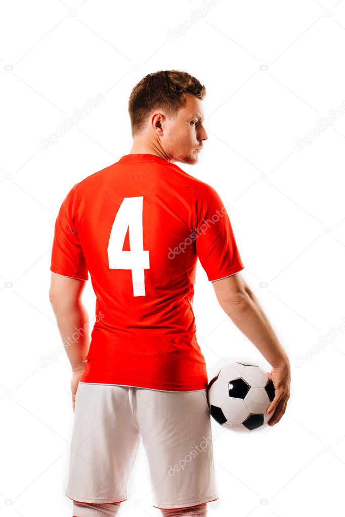 Young soccer player with ball on black background in studio.