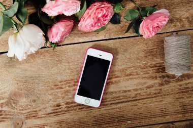 bir çiçekçi bir bitki yanındaki ahşap masa üstünde Smartphone.