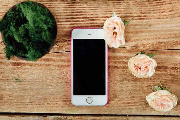 bir çiçekçi bir bitki yanındaki ahşap masa üstünde Smartphone.