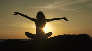 Siluet meditasyon kız lotus pozisyonu çarpıcı deniz arka plan üzerinde taş.