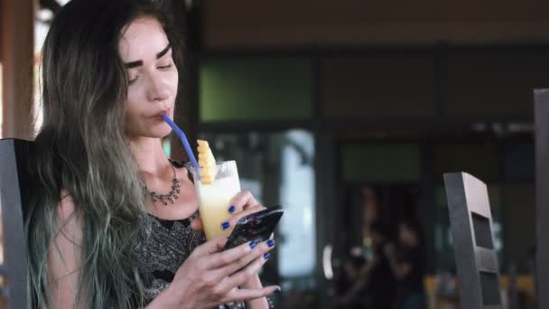 Mulher bonita digitando no telefone durante o dia ensolarado em um café na rua . — Vídeo de Stock