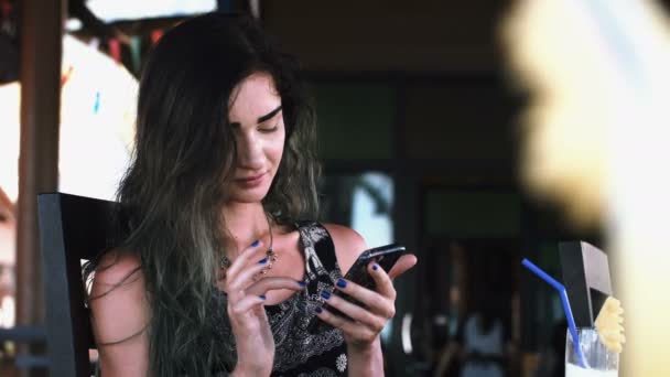 Mulher bonita digitando no telefone durante o dia ensolarado em um café na rua . — Vídeo de Stock