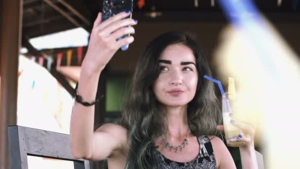 Красивая молодая женщина печатает по телефону в солнечный день в кафе на улице . — стоковое видео