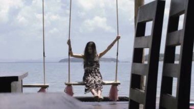 güzel kız deniz iskelede bir kafede karşı bir salıncak üzerinde sürme.