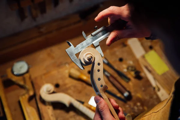 Master artisan instrumentmakare arbetar på skapandet av en fiol rulla. detaljerat arbete på trä med verktyg. — Stockfoto