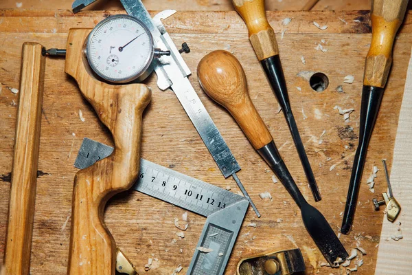 Hulpprogramma's op het bureaublad in de werkplaats. Het maken van een viool. Houtspaanders en stof, creatieve puinhoop. — Stockfoto