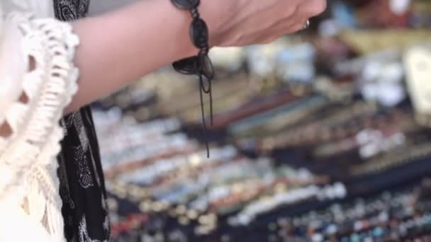 Joven chica sonriente tratando de pulseras de colores en la tienda — Vídeo de stock