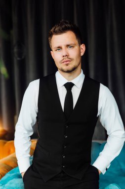 Bir iş kostüm yelek şık spor adamı. Turkuaz koltuk sandalye, ciddi bir göz oturur.