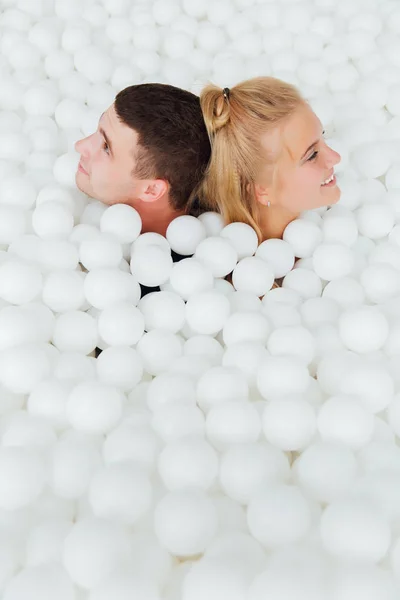Coppia di amici amorevoli divertirsi circondati da palline di plastica bianca in una piscina asciutta . — Foto Stock