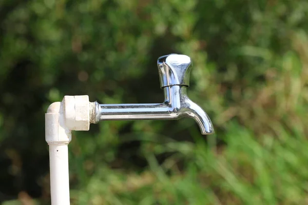 Yeşil arka planı olan metal bir musluk.