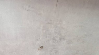 Çiğ beton duvar. Yüzey açık gri. İnce çizikler, çizikler ve koyu lekeler var. Bu da ham ve endüstriyel bir doku oluşturuyor. Basit ama detaylı yüzey kentsel minimalizm hissi veriyor..