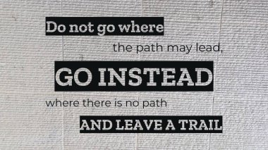 Cesur bir grafik tasarımı, 'Yolun götürebileceği yerlere gitmeyin, yolu olmayan yerlere gidin ve açık renkli, desenli taş bir yüzeye karşı bir yolculuk bırakın' alıntısını sunar.