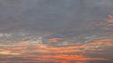 Geniş bir bulutla güzel ve dramatik bir gündoğumu gökyüzü. Üst kısmı yumuşak gri renkte iken, alt yarısı turuncu, pembe ve sarı renkte parlak ve karmaşık bir desen ile patlar..