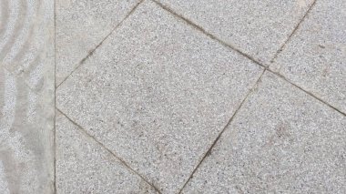 Kabataslak dokuya ve görülebilir harç hatlarına sahip, geometrik desenli geniş kaldırım taşlarının genel görünümü.