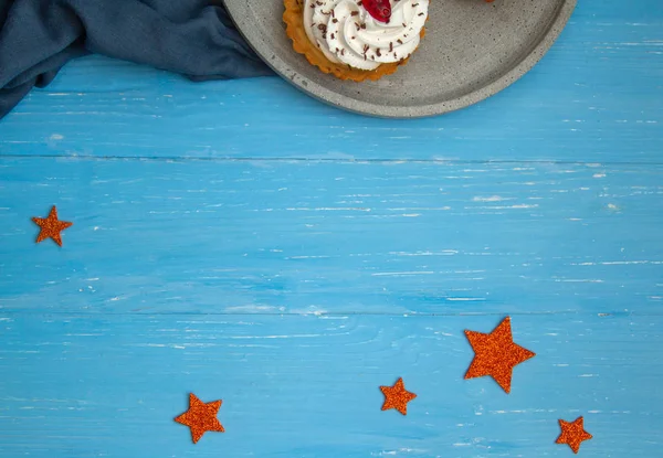 Ciasta Śmietankowe Szarym Talerzu Niebieskim Drewnianym Stole Błyszczące Gwiazdy Dekoracyjne — Zdjęcie stockowe