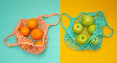 Kompozisyon yukarıdan iki yaprak üzerinde atılıyor - nane ve turuncu. Mandalina ve elmalı iki alışveriş torbası renkli bir arka planda yatıyor.. 