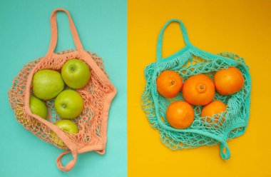 Kompozisyon yukarıdan iki yaprak üzerinde atılıyor - nane ve turuncu. Mandalina ve elmalı iki alışveriş torbası renkli bir arka planda yatıyor.. 