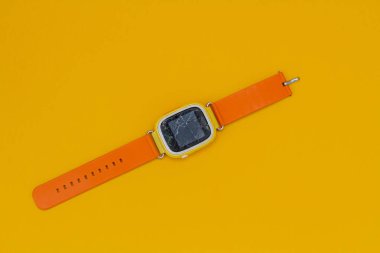 Turuncu arka plandaki akıllı saat. Kırık cam bir aletin üzerinde.
