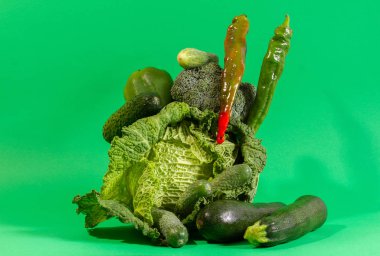 Yeşil arka planda sebze kompozisyonu. Borocoli lahanası, biber ve salatalık gruplandırılır.