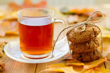 Limonlu siyah çay ve masada kurabiyeler. Sonbahar yaprakları etrafa saçıldı. Güzel, parlak bir arka plan. Lezzetli ve sağlıklı kahvaltı..