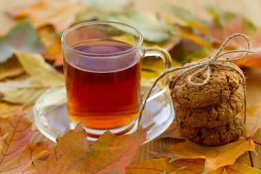 Limonlu siyah çay ve masada kurabiyeler. Sonbahar yaprakları etrafa saçıldı. Güzel, parlak bir arka plan. Lezzetli ve sağlıklı kahvaltı..