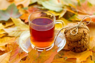 Limonlu siyah çay ve masada kurabiyeler. Sonbahar yaprakları etrafa saçıldı. Güzel, parlak bir arka plan. Lezzetli ve sağlıklı kahvaltı..