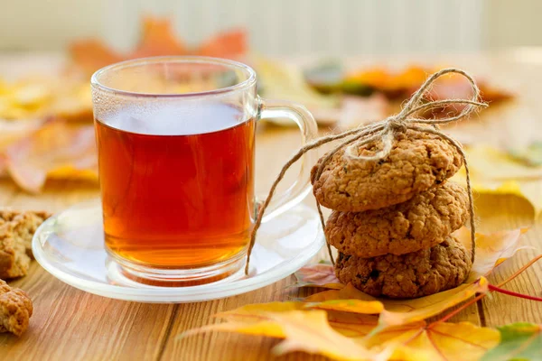Limonlu siyah çay ve masada kurabiyeler. Sonbahar yaprakları etrafa saçıldı. Güzel, parlak bir arka plan. Lezzetli ve sağlıklı kahvaltı.