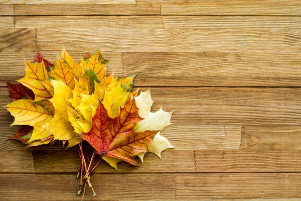 Ahşap bir masanın üzerinde sonbahar yapraklarından oluşan bir buket. Güzel sonbahar arkaplanı.