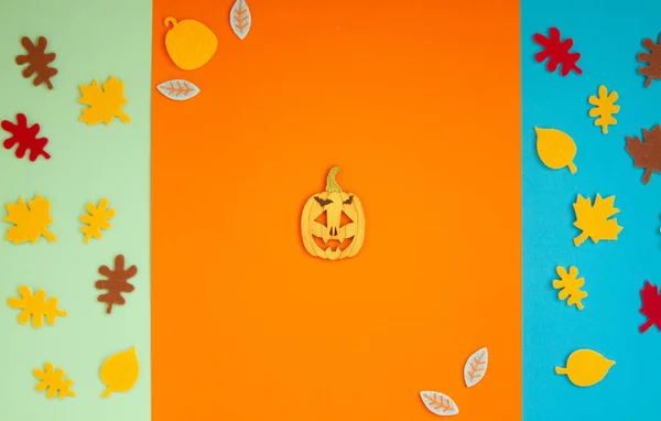 Paper leaves for Halloween party are laid out on an orange background.