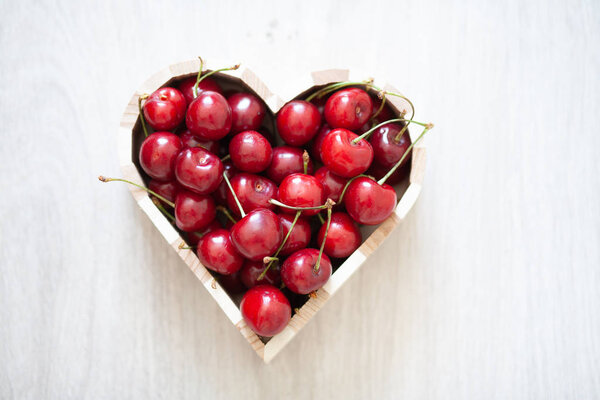 Delicious sweet ripe and juicy berries. Sweet cherries lies in a box in the form of a heart