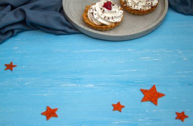 Bir tabakta üç kremalı kek. Ahşap mavi bir masada Noel kompozisyonu