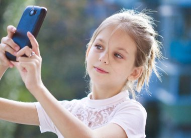 Küçük kız akıllı telefonuyla selfie çekiyor.
