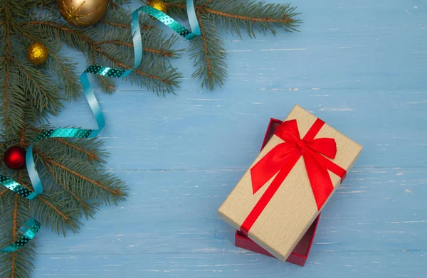 Ahşap bir arka planda güzel bir hediye kutusu. Noel ağacı dalları masanın üstünde. Mutlu yıllar.!