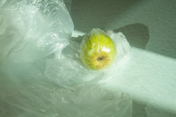 Ripe pear in cellophane bag. The problem and the concept of ecologists on planet Earth. Plastic is bad for food