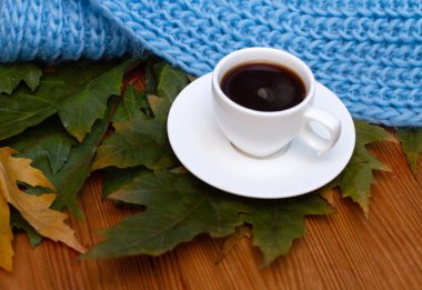  Masadaki sonbahar yapraklarının üzerinde bir fincan kahve.