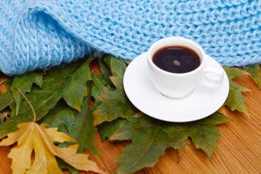  Masadaki sonbahar yapraklarının üzerinde bir fincan kahve.