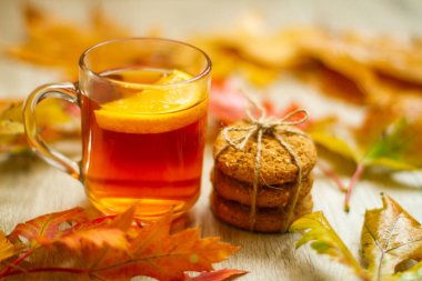 Limonlu siyah çay ve masada kurabiyeler. Sonbahar yaprakları etrafa saçıldı. Güzel, parlak bir arka plan. Lezzetli ve sağlıklı kahvaltı.. 