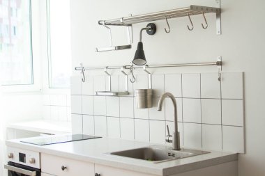 Parlak bir mutfak, en az eşya ve mobilya, ön planda bir musluk ve lavabo..