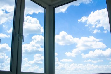 Mavi gökyüzünde beyaz bulutlar, bir apartman penceresinden manzara, gökyüzü manzaralı büyük pencereler..