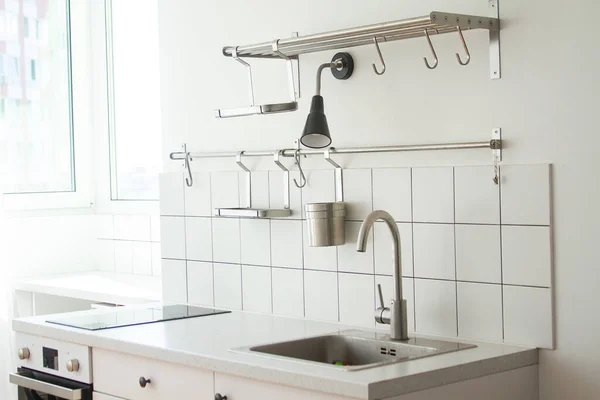 Parlak bir mutfak, en az eşya ve mobilya, ön planda bir musluk ve lavabo..