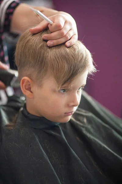 小さなかわいい男の子がスタイリストの美容室に座っています 子供は美容室で髪を切っています 理容室で子供 短い男性の散髪 — ストック写真