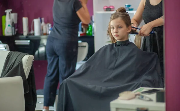 美しい若いヨーロッパの女の子は美容室に座っています 女の子の長い髪を持つプロの美容師の作品 — ストック写真